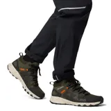 Bota de senderismo Columbia Peakfreak II Mid Outdry, color verde oliva con detalles en negro y naranja. Presenta tecnología impermeable OutDry, sistema de ajuste Navic Fit y entresuela TechLite+ para mayor amortiguación. Suela Adapt Trax con tracción superior y diseño de altura media para soporte en el tobillo.
