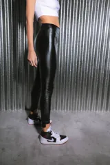 Calzas negras de bengalina engomada brillante, tiro alto y botamanga irregular.