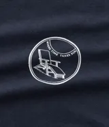 Remera azul marino de algodón con cuello redondo y manga corta. Estampa localizada en el frente con temática resort club y silla de playa.