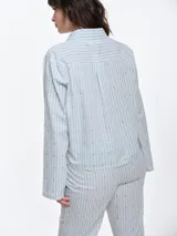 Camisa de dormir de popelina de algodón, con estampado de rayas verticales y pequeños motivos geométricos. Presenta cuello camisero, mangas largas y cierre frontal mediante lazos ajustables.