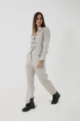 Pantalón sastrero de lino color gris claro melange, de tiro medio, con corte flojo que se afina suavemente hacia los tobillos. Cuenta con bolsillos frontales con detalles de pasamanería a rayas.