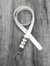 Cinto blanco de cuero sintético con hebilla metálica plateada y trabilla con apliques metálicos.