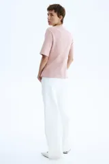 Remera de punto interlock pesado en color rosado, con cuello redondo y mangas cortas. Presenta cintura entallada con pinzas moldeadoras en la parte delantera que generan un sutil efecto peplum.