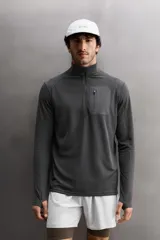 Camiseta de manga larga negra, confeccionada en tejido técnico ligero y elástico. Tiene cuello alto con cremallera, corte slim fit, bolsillo frontal con cremallera y puños con cinta a contraste.