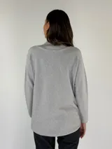 Sweater de punto color gris claro, con cuello alto y mangas largas.