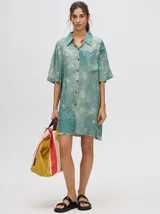 Vestido camisero corto oversize de viscosa con estampado tie-dye en tonos verde agua y blanco, cuello camisero, mangas cortas y bolsillo aplicado en el pecho.