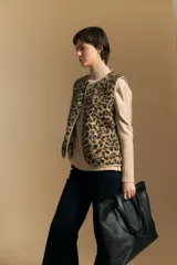 Chaleco de textura afelpada con estampado animal print, cuello redondo y cierre frontal con botones a presión. Cuenta con bolsillos laterales y ribetes al tono.