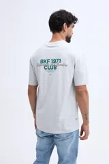 Remera oversize negra de manga corta, con calce amplio y estampa gráfica en la espalda con texto en tonos azules y dorados.