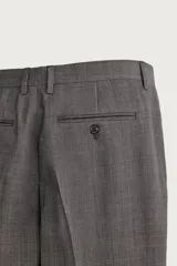 Pantalón de vestir regular fit color gris con sutil patrón a cuadros, confeccionado con mezcla de lana. Cuenta con bolsillos frontales, bolsillos traseros de doble vivo con botón, trabillas para cinturón y raya marcada en las piernas.