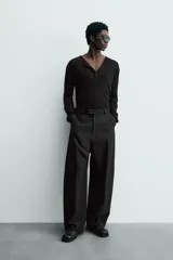 Jersey negro de punto fino, con cuello pico profundo y mangas largas. Terminaciones acanaladas.