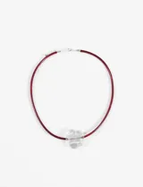 Collar con cordón de gamuza color bordó y dije de acrílico transparente con forma de flor.