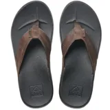Sandalias tipo ojota Reef con base negra texturizada y tiras de cuero marrón con logo grabado.