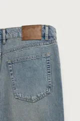 Jeans de corte recto y tiro medio confeccionados en denim de algodón con efecto lavado, diseño de cinco bolsillos y cierre frontal con cremallera y botón.