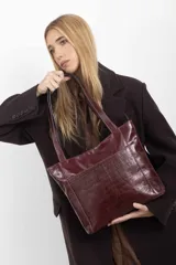 Cartera tipo tote de cuero vacuno negro con doble asa de hombro, panel superior liso y bolsillo exterior frontal con textura símil cocodrilo y costuras visibles en contraste.