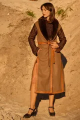 Abrigo largo tipo bata con diseño envolvente y cinturón de cuero. Presenta mangas acolchadas con patrón capitonado, cuerpo de tweed con vivos de cuero y solapa con detalle de corderito.