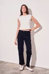 Pantalón de jean negro, de corte recto y tiro medio. Presenta bolsillos delanteros y traseros, y una hilera de botones metálicos a lo largo de la costura lateral.