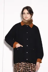 Campera negra con cuello y puños de pana marrón, cierre frontal con botones a presión y bolsillos delanteros con solapa. Diseño acolchado con costuras en forma de rombos.