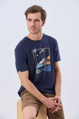 Remera azul marino de manga corta con cuello redondo y estampa frontal de un paisaje de playa con palmeras y el texto 'Legacy Beach Club'.