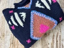 Sweater tejido de lana color azul marino con diseño geométrico en blanco.