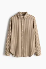 Camisa de manga larga con estampado de rayas verticales en tonos marrón y blanco. Presenta cuello clásico, cierre frontal con botones, puños abotonados y bajo redondeado.