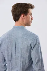 Camisa de lino y algodón color beige, de manga larga, con cuello mao y cierre frontal con botones. Presenta un pequeño bordado al tono en el pecho.