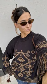 Buzo de punto negro con diseño geométrico y floral en tono marrón, de cuello redondo y manga larga.