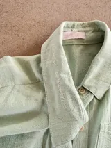 Camisa de manga larga color verde menta con cuello camisero, bordado con la frase "mon amour" en la solapa del cuello, cierre frontal con botones y bolsillo ojal en el pecho. Marca Bartola.