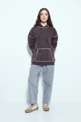 Buzo canguro de calce relajado, color marrón con efecto lavado y costuras a la vista en contraste. Cuenta con capucha integrada y bolsillo frontal tipo canguro.