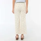 Pantalón de corte wide leg en color crudo con estampado floral pequeño, tiro alto, bolsillos frontales y cierre con botón y cremallera.