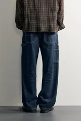 Pantalón jeans de corte relaxed fit, color celeste con efecto lavado, de estilo carpintero con bolsillos laterales y presillas de herramientas.