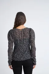 Blusa rosa con estampado de flores blancas y amarillas, cuello en V, manga larga abullonada y cierre frontal con botones.