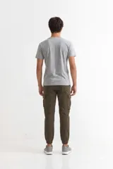 Pantalón tipo jogger cargo de hombre, color verde militar, con cordón ajustable en la cintura y puños elásticos en los tobillos. Presenta bolsillos cargo con solapa en ambos muslos.