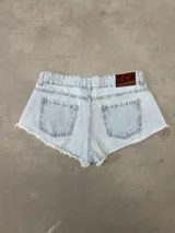 Short de jean tiro bajo color celeste claro, con diseño de corte muy corto y dobladillo desmechado con flecos.