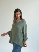 Sweater de punto calado en color verde seco, con escote redondo, mangas largas anchas y diseño holgado.