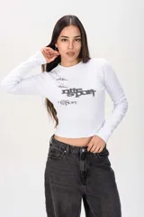 Remera blanca de manga larga y corte ajustado, confeccionada en tejido rib con diseño estampado en el frente.
