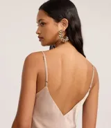 Vestido midi color beige confeccionado en satén texturizado, con breteles finos y escote drapeado.