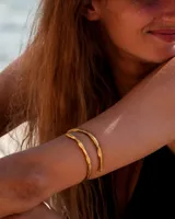 Brazalete rígido de diseño minimalista con forma de espiral, elaborado artesanalmente en bronce y alpaca maciza. Es una pieza ajustable que puede lucirse tanto en el antebrazo como en la parte superior del brazo.