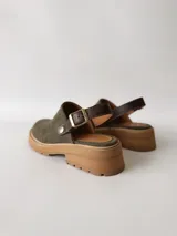 Zuecos de cuero color verde seco, con hebilla lateral y suela de goma.