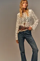 Top de encaje negro con cuello redondo, manga larga y hombreras incorporadas. Presenta un diseño de corte recto y cierre posterior.