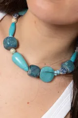 Collar corto de diseño artesanal confeccionado con piedras naturales y cuentas en tonos turquesa, azul y blanco con detalles estampados.