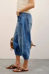 Jean de tiro medio-alto y calce holgado, con piernas anchas que se estrechan hacia el tobillo y largo midi. Confeccionado en denim rígido con lavado bleach y cierre frontal con botones.