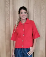 Cardigan de punto color arena, con cuello camisero, cierre frontal de botones y mangas cortas con terminación acanalada. Presenta dos bolsillos frontales tipo parche.