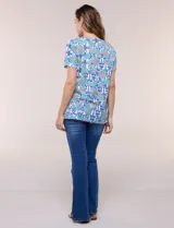 Blusa de manga corta con escote en V y pechera bordada. Presenta un estampado multicolor sobre base blanca, con pliegues frontales y aberturas laterales en el ruedo.