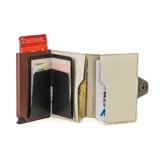Billetera tarjetero automática con estructura de aluminio y revestimiento de cuero bicolor en tonos verde oliva y beige. Cuenta con un cierre de broche a presión y el logo de la marca grabado en la parte inferior.