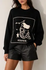 Sweater de punto negro con diseño oversize, cuello redondo y mangas largas. Cuenta con un bordado artesanal en la parte frontal que representa el signo zodiacal de Acuario en color crudo dentro de un marco rectangular.