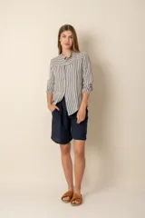 Camisa de lino a rayas verticales azules y blancas, con cuello mao, manga larga con puño elástico y cierre frontal con botones.