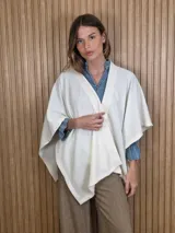 Ruana de tejido waffle color blanco marfil, con diseño abierto, corte asimétrico y bordes ribeteados.