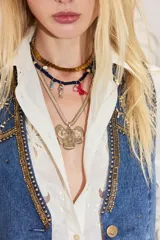 Collar de metal dorado con cadena de diseño plano en forma de espiga y un gran dije colgante en forma de flor texturizada.