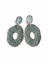 Aros colgantes artesanales de resina y metal plateado, con diseño texturizado en tonos celestes y plateados, adornados con bordes de strass.