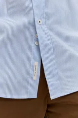 Camisa celeste de manga larga con cierre frontal de botones y cuello clásico.